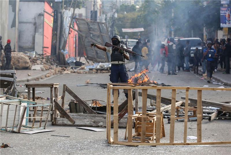 Berichte: Banden greifen Regierungsgebäude in Haiti an Die Polizei sichert eine Straßensperre, die von Demonstranten errichtet wurde.