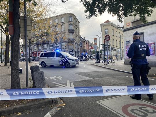 Die Polizei sperrt eine Straße, während ein Polizist hinter Absperrband Wache steht.