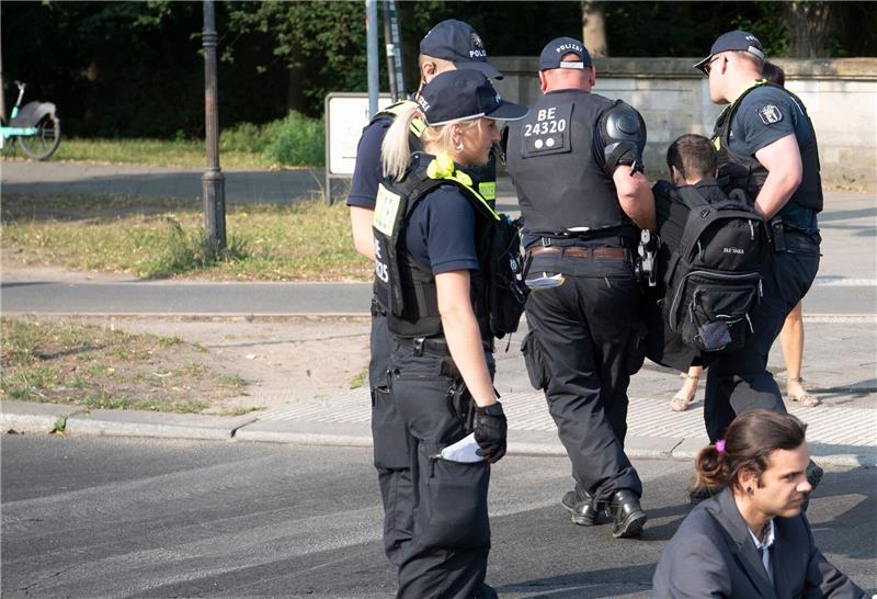 Klimaaktivisten stören bundesweit den Verkehr Die Polizei trägt einen Aktivisten der Gruppe Letzte Generation weg, der mit anderen die Fahrbahnen rund um die Siegessäule in Berlin blockiert hat.