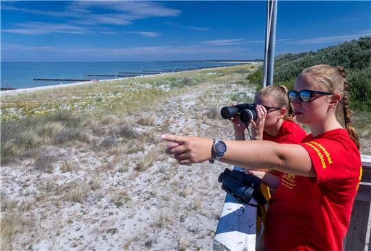 Die Rettungsschwimmerinnen Linda (hinten) und Charlotte beobachten vom Hauptturm der DLRG am Ostseestrand auf der Halbinsel Darss-Fischland-Zingst den Badebetrieb.