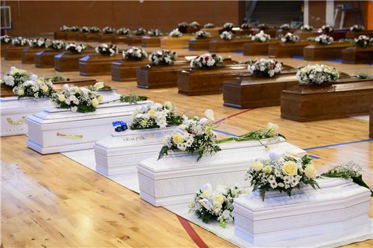 Die Särge der Opfer eines Bootsunglücks stehen mit Blumen bedeckt in der örtlichen Sporthalle.