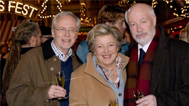 Vor fünf Jahren endete die „Lindenstraße“ Die Schauspieler Joachim Hermann Luger (Hans Beimer, links) und die Schauspieler Marie-Luise Marjan (Mutter Beimer) und Bill Mockridge (Erich Schiller, rechts) posieren in der Außenkulisse mit Sektgläsern nach der Live-Ausstrahlung der 1559. Folge im Dezember 2015.