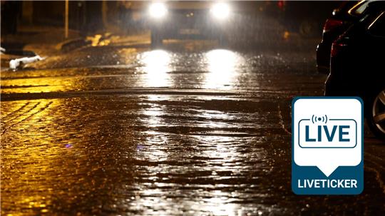 Die Scheinwerfer eines Autos spiegeln sich auf der teilweise vereisten Straße.