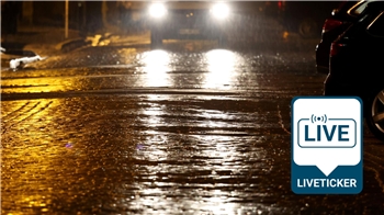 Die Scheinwerfer eines Autos spiegeln sich auf der teilweise vereisten Straße.