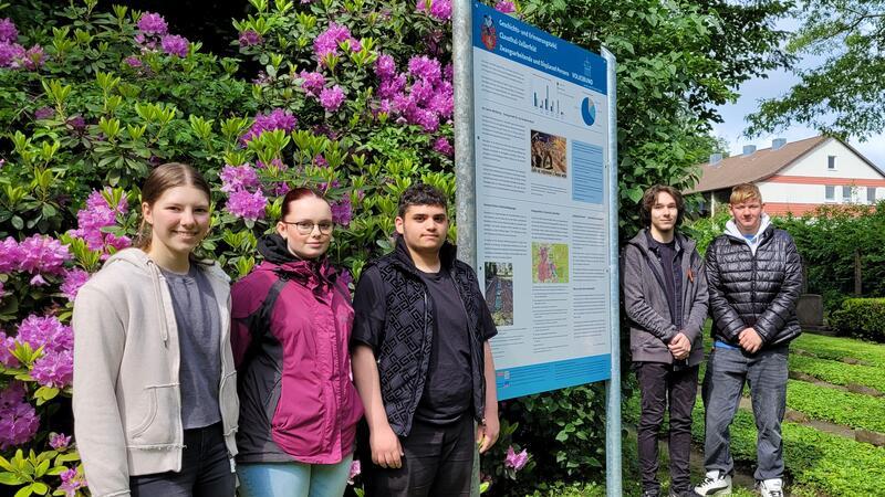 Oberharzer Schüler arbeiten die Schicksale von Zwangsarbeitern auf Die Schüler neben ihrer Tafel, hinter ihnen die Gräber der Zwangsarbeiter.