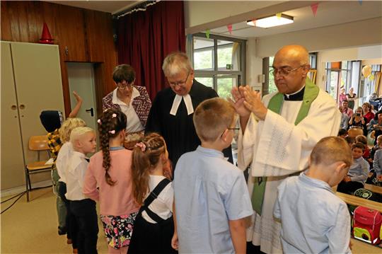 Die Schulanfänger erhalten während der Einschulungsfeier auch eine Segnung und Fürbitte vom evangelischen Pfarrer Dirk Glufke und katholischen Pater Cyriac Chandrankunnel (v. li). Foto: Jambrek