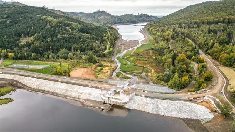 Eine gebirgige Landschaft mit einem Fluss, der von einer Talsperre getrennt ist.