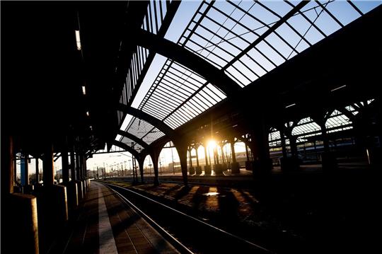 Die Sonne geht am Morgen hinter der historischen Gleishalle am Hauptbahnhof auf.