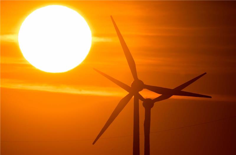 Statkraft will in Deutschland investieren Die Sonne geht hinter Windrädern auf.