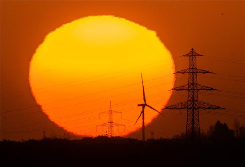 Weil fordert Energienetzausbau mit Steuergeld Die Sonne geht hinter Windrädern und Hochspannungsleitungen in der Region Hannover auf.