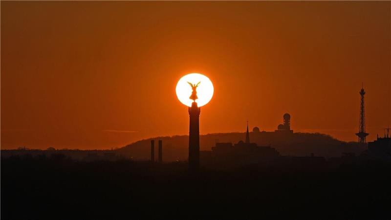 Die Sonne geht hinter der Siegessäule in Berlin unter.