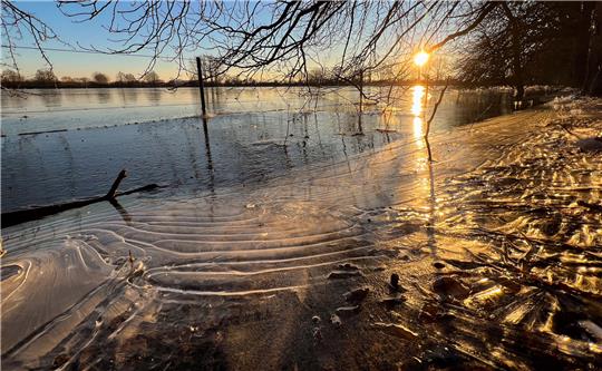 Die Sonne geht in der beim Hochwasser überfluteten Leinemasch südlich von Hannover unter. Temperaturen deutlich unter dem Gefrierpunkt verwandeln die überfluteten Wiesen und Felder derzeit in riesige Eisflächen. Foto: Julian Stratenschulte/dpa