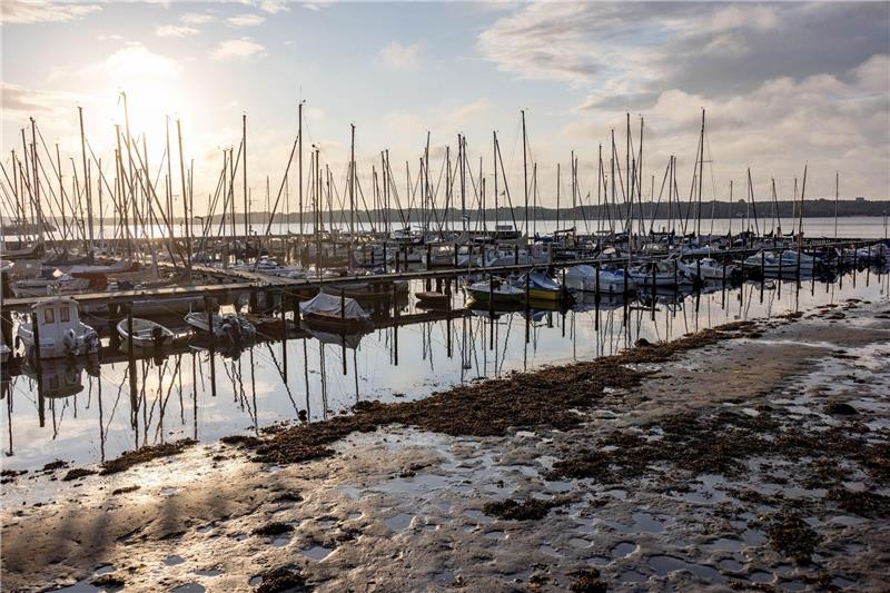 Ruhe und Sonne nach Feuerwehreinsätzen wegen Sturm „Poly” Die Sonne scheint auf einen Bootshafen an der Kieler Förde, aus dem das Sturmtief «Poly» das Wasser herausgedrückt hat, so dass die normalerweise mit Wasser bedeckten Ufer trocken liegen.