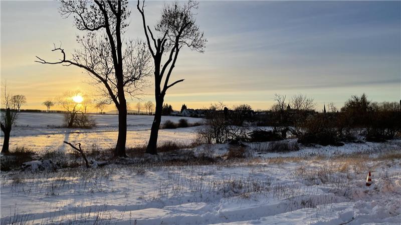 Sonnenuntergang über schneebedeckter Landschaft.