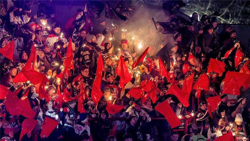 Menschenmenge bei Nacht mit roten Fahnen und Fackeln in der Hand.