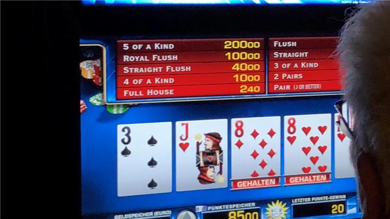 Das Bild zeigt eine Frau, die vor einem Geldspielautomaten sitzt.