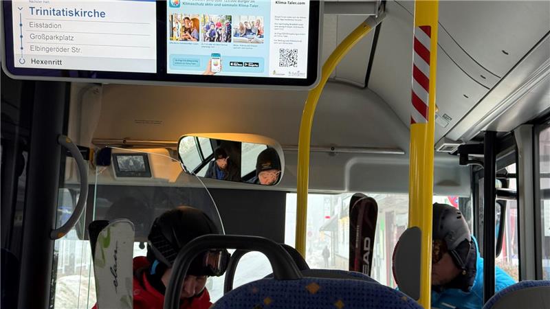 Das Foto zeigt zwei Wintersportler, die mit Skiern in einen Bus einsteigen.