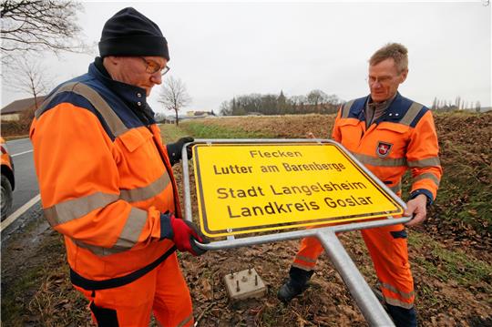 Die Straßenwärter Ralf Immemroth und Thomas Gebers (v.li.) montieren am Lutteraner Ortseingang eines der neuen Schilder.  Fotos: Gereke