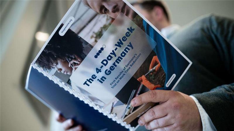 Studie: Vier-Tage-Woche macht produktiver und zufriedener Die Studie zur Vier-Tage-Woche in Deutschland in den Händen eines Teilnehmers der Pressekonferenz.