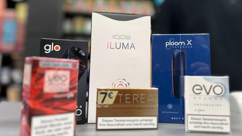 Die Tabakerhitzer-Elektrogeräte der Marken Glo von British American Tobacco (BAT), Iqos von Philip Morris und Ploom von Japan Tobacco International (JTI) mit den dazugehörigen Tabakstick-Marken liegen auf der Verkaufstheke eines Geschäfts.