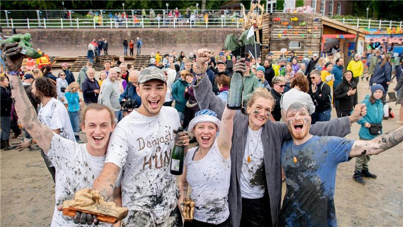 Deutsche Meister im Schlickrutschen gekürt Die Teilnehmerinnen und Teilnehmer „Das andere Wiesel“ (von links), „Dangaster Hüne“, „Aldi-Anna“, „Schlick-Schlack-Schlea“ und „Flo“ jubeln nach dem Finale der deutschen Meisterschaften im Schlickrutschen im Rahmen des Watt en Schlick Fest am Strand von Dangast.