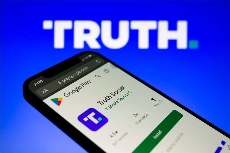 Trumps Twitter-Alternative künftig in Googles App Store Die Truth-App von Trump-Media wird im Google Play Store auf einem Smartphone mit dem Logo im Hintergrund angezeigt.