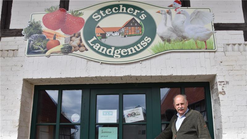 Eingang eines Fachwerkgebäudes mit Schild 'Stecher's Landgenuss' und Abbildungen von Gemüse, Huhn und Wurstwaren