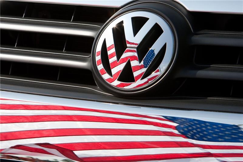 VW und BMW müssen in den USA Autos in die Werkstätten rufen Die US-Fahne spiegelt sich in Logo und Kühlergrill eines Volkswagen-Fahrzeugs.