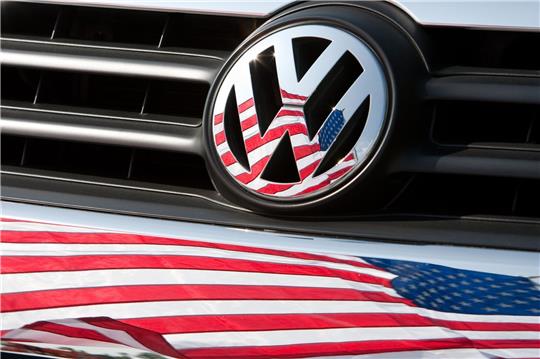 Die US-Fahne spiegelt sich in Logo und Kühlergrill eines Volkswagen-Fahrzeugs.