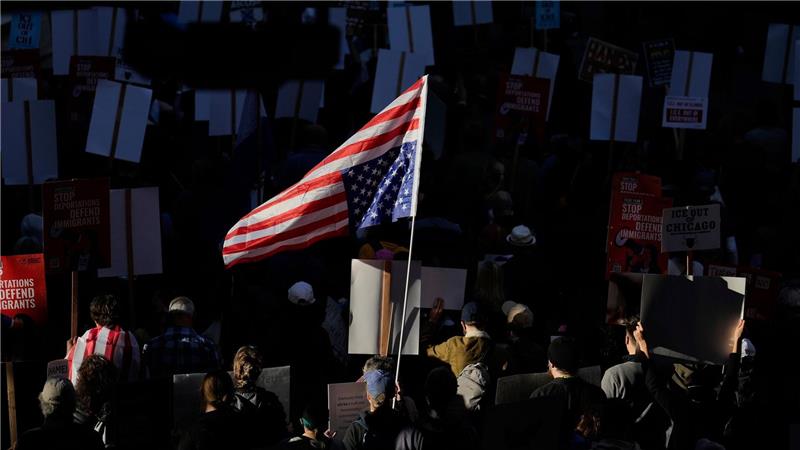Die US-Flagge wird bei einem Demonstrationszug durch Chicago von der Sonne angestrahlt.