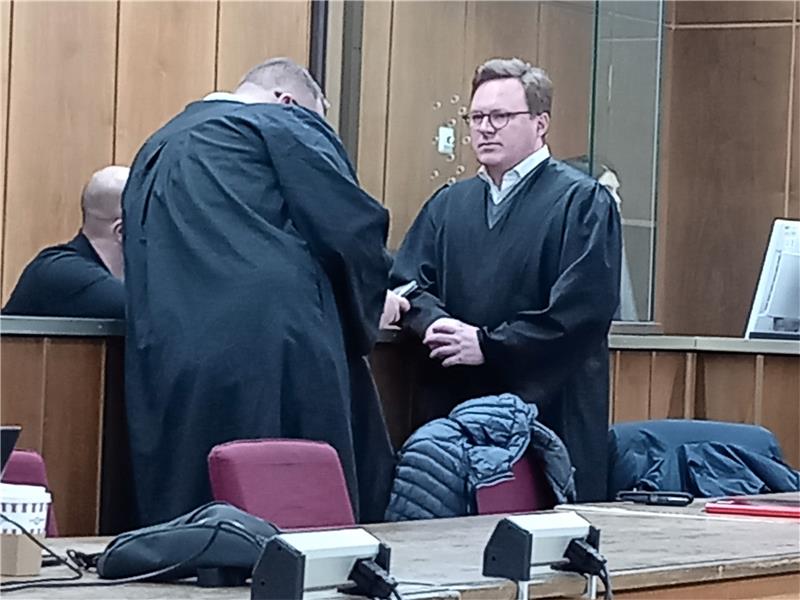Kokain-Prozess: „Lion“ legt ein Teilgeständnis ab Die Verteidiger Raban Funk (li.) und Pascal Ackermann schirmen ihren Mandanten (halb verdeckt) zu Prozessbeginn meist gegen Fotografen ab und erörtern noch einmal das weitere Vorgehen im Verfahren. Foto: Neddermeier