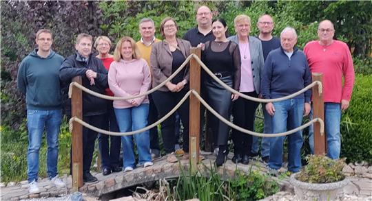 Gruppe von Menschen steht auf einer kleinen Holzbrücke in einem Garten