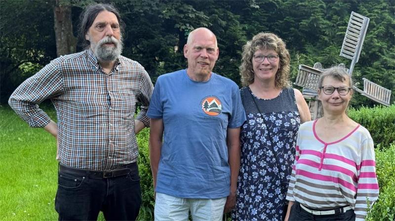 Zwei Männer und zwei Frauen stehen vor einer Windmühle.