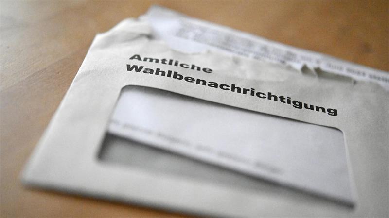 Briefumschlag mit der Aufschrift 'Amtliche Wahlbenachrichtigung' auf einem Holztisch