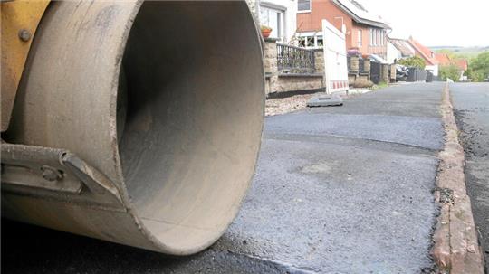 Die Walze steht in Döhren am Straßenrand, vor ihr glänzt der frische Asphalt.