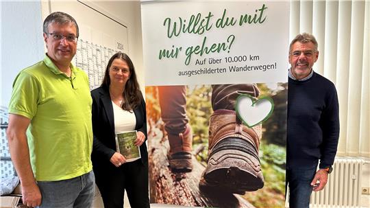 Die Wander-Werbeaktion, bei der Cathleen Hensel mit den Wanderführern Jörg Kühnhold (l.) und Axel Günther (r.) auf das Angebot aufmerksam machen will, zeigt es deutlich: Alle drei Orte Braunlage, St. Andreasberg und Hohegeiß sind auf dem Fuß des Plakats vertreten. Das ist lang, lässt sich nicht so gut bewerben und oft auch schlecht platzieren, heißt es.