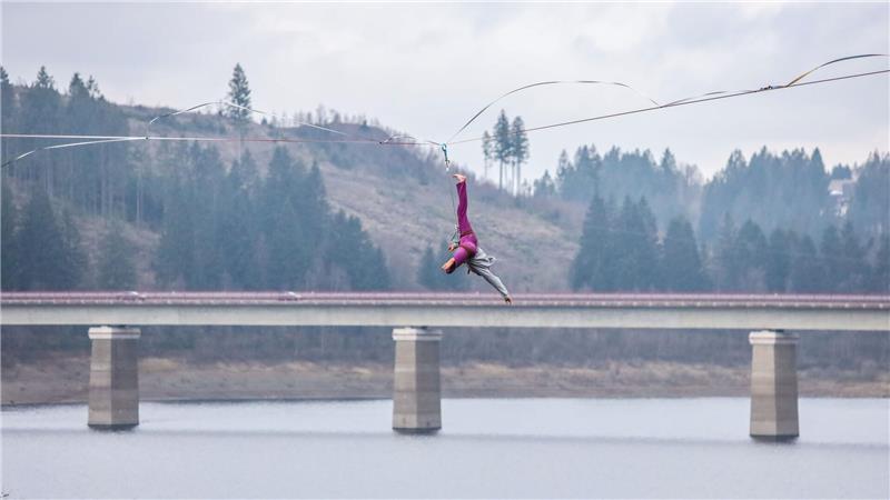 Die Weißwasserbrücke im Hintergrund: Selbst wenn die Sportler stürzen, sind sie mit einem Klettergurt an dem Balancierband befestigt.