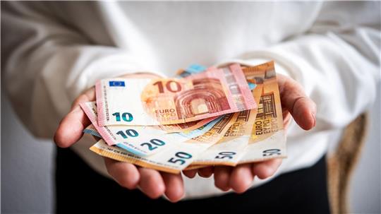 Eine Person hält sechs Geldscheine in ihren Händen.