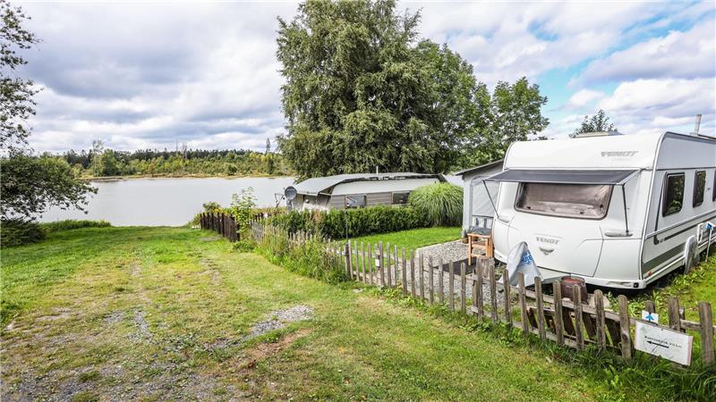 Der Campingplatz Prahljust liegt idyllisch am Pixhaier Teich. Im Vordergrund ist ein Wohnwagen zu sehen.