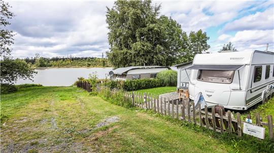 Der Campingplatz Prahljust liegt idyllisch am Pixhaier Teich. Im Vordergrund ist ein Wohnwagen zu sehen.