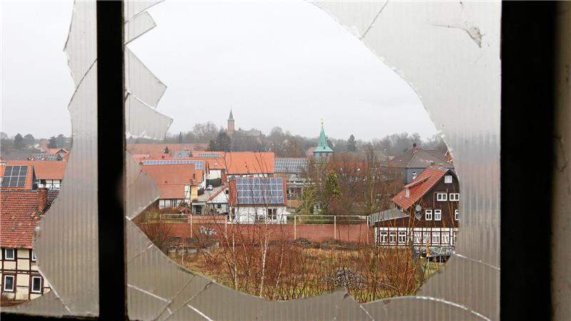 Lost Place: Hoffnung für denkmalgeschützte Gebäude in Schladen Durch eine zerbrochene Scheibe fällt der Blick auf ein Dorf, aus dem sich zwei Kirchtürme erheben.