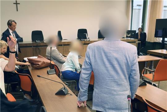 Die angeklagten Eltern sitzend und der angeklagte Arzt im Oberlandesgericht München.