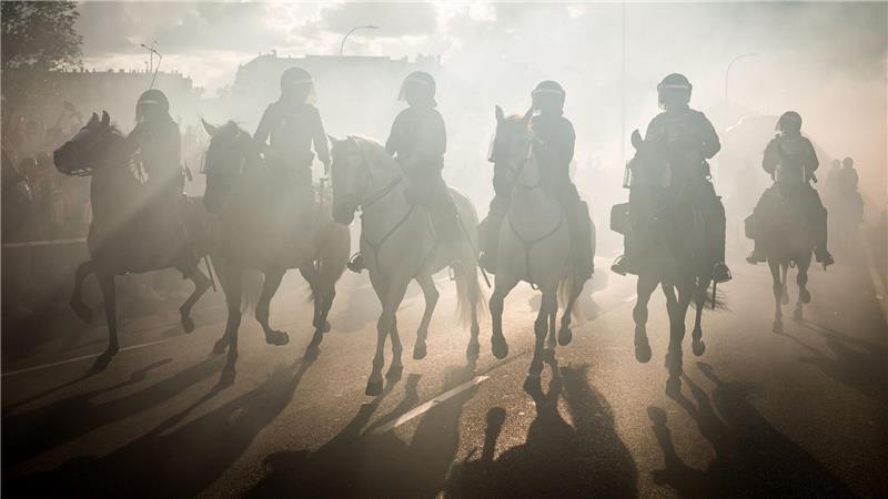 Die berittene Polizei reitet im Rauch während der Einsätze im Vorfeld des Spiels Atlético Madrid gegen FC Arsenal in der Champions League.