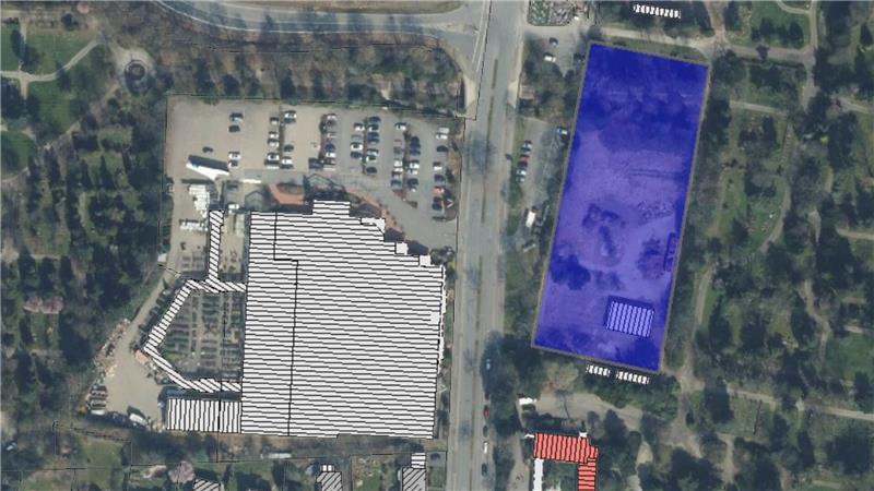 Luftaufnahme eines Parkplatzes mit zwei markierten Flächen, eine links in Weiß und eine rechts in Blau