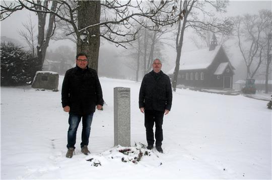 Die ersten drei Schilder sind bereits an der Stele auf dem Gräberfeld befestigt, an der Bürgermeister Wolfgang Langer (links) und Pfarrer Andreas Widlowski stehen. In den nächsten Tagen soll auch die Kapelle im Hintergrund saniert werden, der Fachausschuss empfiehlt dem Rat jedenfalls, Mittel dafür bereitzustellen.  Foto: Eggers