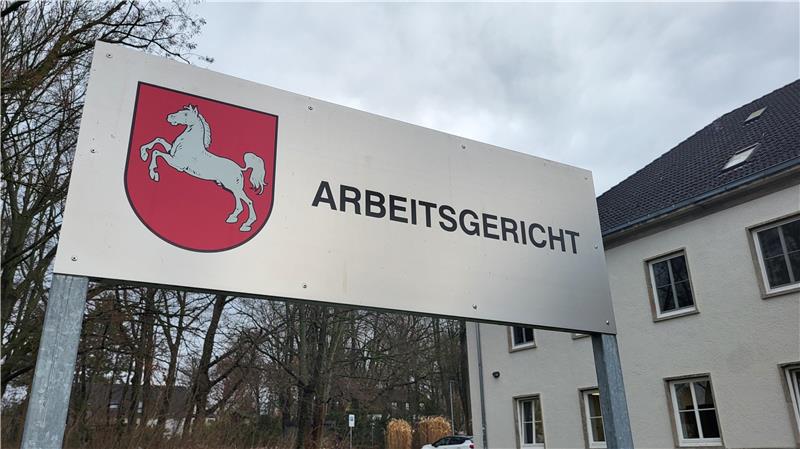 Schild mit rotem Wappen und weißem Pferd sowie der Aufschrift 'ARBEITSGERICHT' vor einem Gebäude und kahlen Bäumen