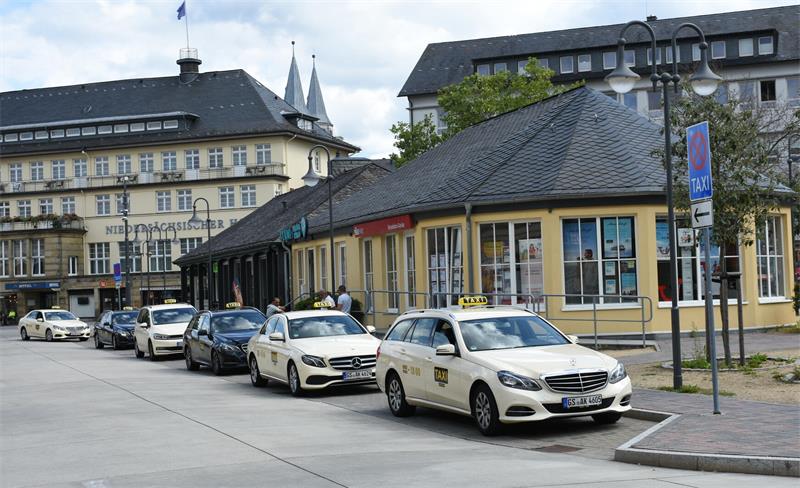 Taxen stehen in einer Reihe vor einem Gebäude mit Schieferdach.