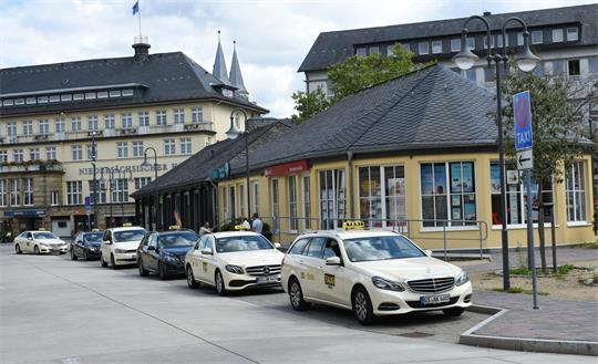 Taxen stehen in einer Reihe vor einem Gebäude mit Schieferdach.