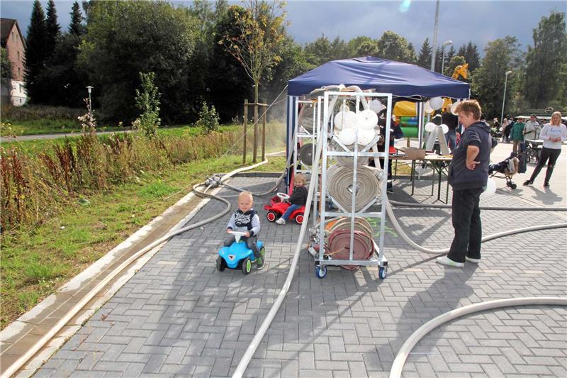 Die jüngsten Besucher haben ihren Spaß, indem sie mit einem Bobby-Car den Schlauch-Parcours abfahren, den die Helfer der Wehr vorher gelegt haben.