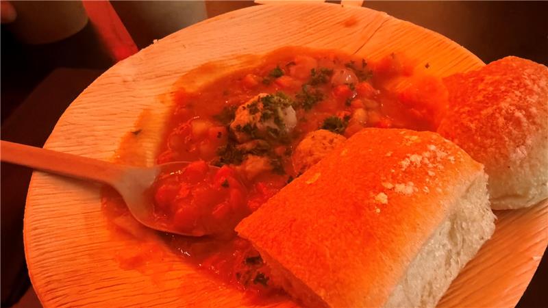 Das Foto zeigt eine Möhrensuppe mit zwei Brötchen in einer Holzterrine.